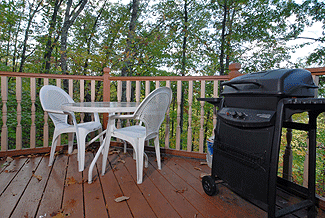 gas grill on a deck with a wooded view