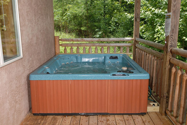 Pigeon Forge Log Cabin that features an outdoor hot tub