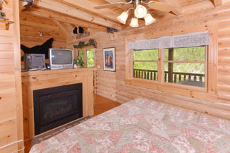 Pigeon Forge Cabin Rental Open bedroom with a gas fireplace in the main level living room area