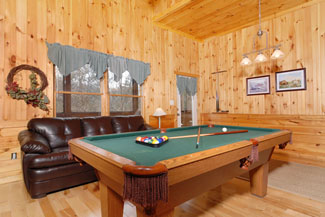 Gameroom area that features a gas fireplace sleeper sofa and a pool table