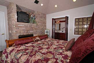 king size bed in the master bedroom with a gas fireplace