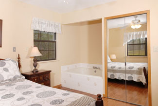 Pigeon Forge Two Bedroom Plus Loft Cabin that has a main level master bedroom that features hardwood floors and a whirl pool.