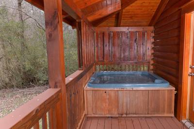Pigeon Forge One Bedroom Cabin Rental featuring a hot tub on the deck overlooking the Little Pigeon River